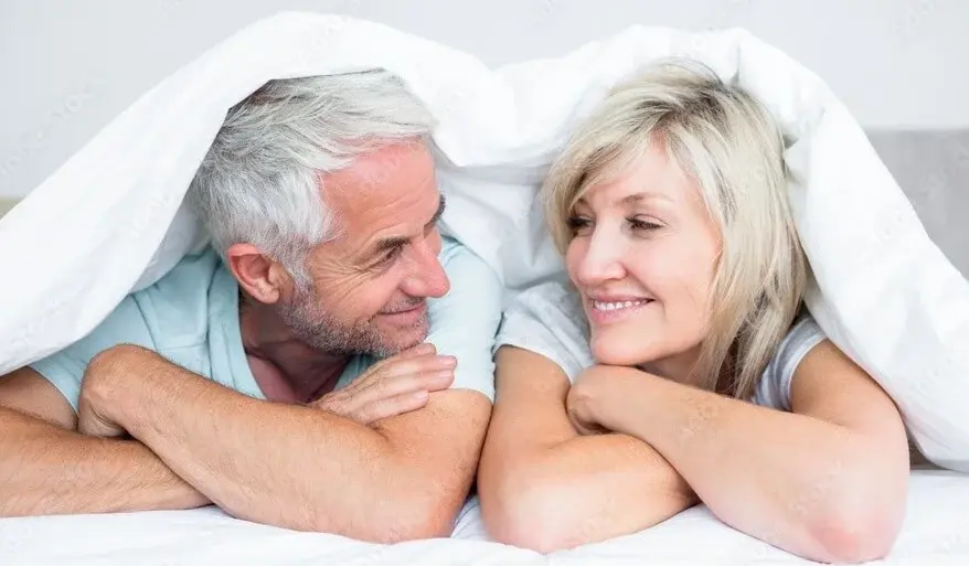 Couple staying in bed under a blanket