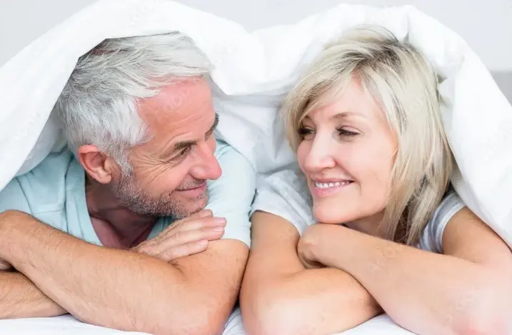 Couple smiling at eachother under the covers
